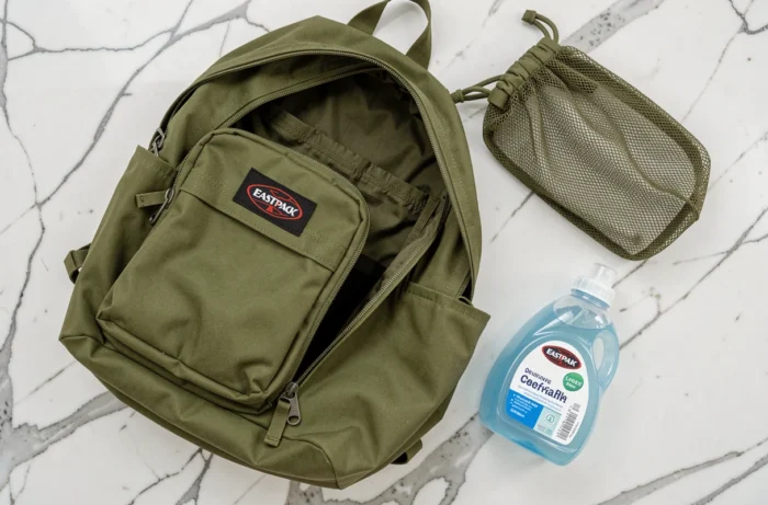 Préparation d'un sac Eastpak vert avant lavage en machine avec filet de protection et lessive douce